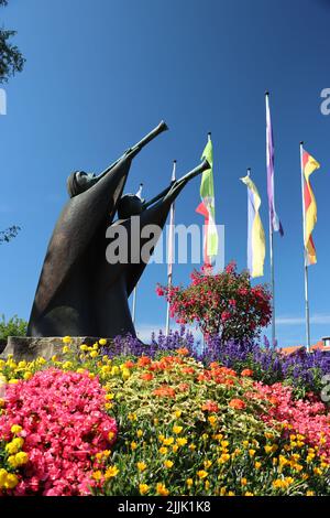 statue avec trompette. profitez de leurs trompettes en été avec ciel bleu et fleurs dans le jardin public. Banque D'Images