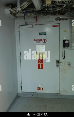 Intérieur de la salle des moteurs des bateaux de croisière avec portes étanches moteurs électriques et diesel, tuyaux d'eau, instruments de mesure, panneaux d'avertissement Banque D'Images