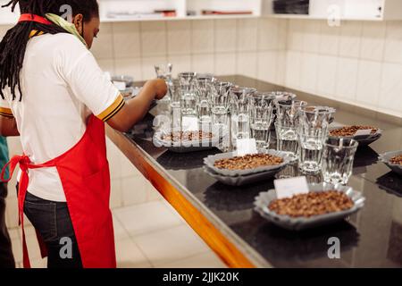 Femme afro-américaine mettant des notes sur des assiettes avec du café pour la dégustation Banque D'Images