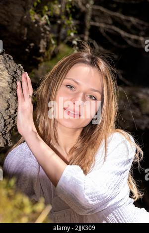 femme blonde dans une robe blanche assise dans la forêt Banque D'Images