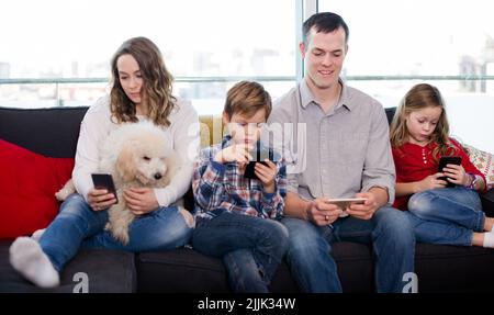 Les membres de la famille souriants passent du temps à jouer avec un smartphone Banque D'Images