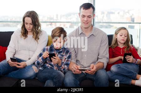 Les membres de la famille sont joyeux et passent du temps à jouer avec leur téléphone intelligent Banque D'Images