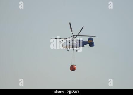 Hélicoptère lourd de l'INFOCA transportant un seau d'eau pour se déposer sur un feu de forêt, Mijas, Espagne. Banque D'Images
