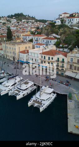 Une photo verticale de bateaux amarrés dans un port contre des bâtiments de l'île d'Hydra, en Grèce Banque D'Images