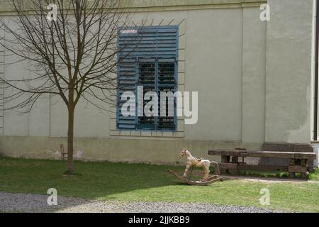 Un vieux cheval à bascule en bois devant un bâtiment en pierre Banque D'Images