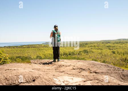 Une vue arrière d'un touriste caucasien dans une casquette de basket-ball debout sur le rocher et appréciant la vue Banque D'Images