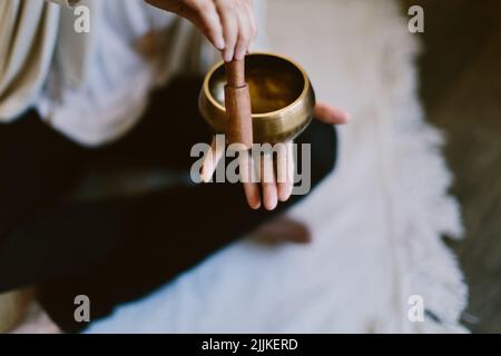 Une photo d'angle d'une femme utilisant un bol de chant de méditation tibétain. Banque D'Images