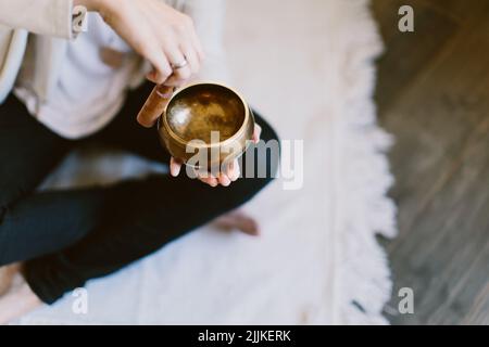 Une photo d'angle d'une femme utilisant un bol de chant de méditation tibétain. Banque D'Images