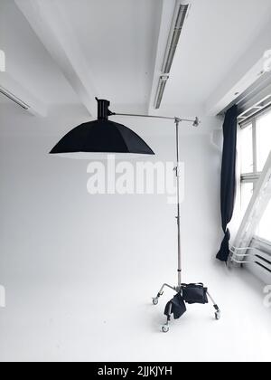 Flash photo professionnel avec une grande softbox sur un pied en C sur un cyclorama dans un studio photo moderne avec de grandes fenêtres. Éclairage professionnel Banque D'Images