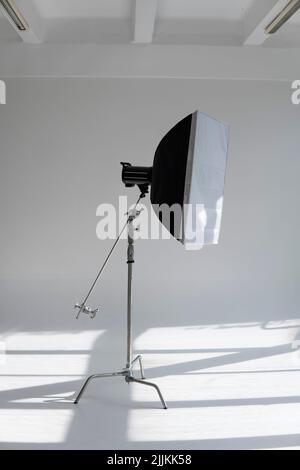 Flash photo professionnel avec une grande softbox sur un pied en C sur un cyclorama dans un studio photo moderne avec de grandes fenêtres. Éclairage professionnel Banque D'Images