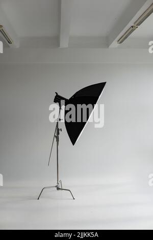 Flash photo professionnel avec une grande softbox sur un pied en C sur un cyclorama dans un studio photo moderne avec de grandes fenêtres. Éclairage professionnel Banque D'Images