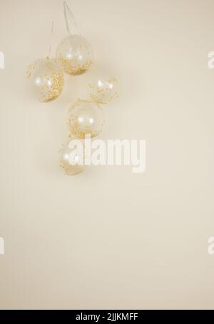 Ballons confettis d'or et de crème monochromatiques transparents sur fond jaune clair et crémeux Banque D'Images