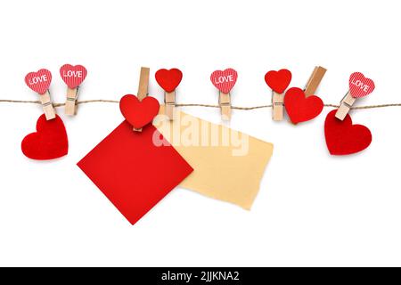 Épingles à linge en bois avec coeurs et feuilles de papier blanc accrochées à un fil de lin. Concept pour la Saint Valentin. Carte de vœux. Espace pour votre texte. Banque D'Images