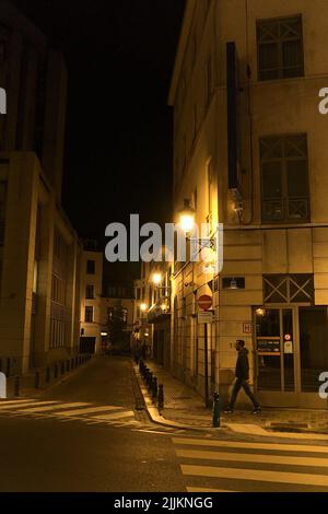 Une photo verticale d'un homme qui marche dans la rue de nuit Banque D'Images
