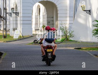 Galle, Sri Lanka - 02 03 2022: Couple touristique explorant le fort de Galle, à bord d'une moto portant deux casques rouges. Banque D'Images