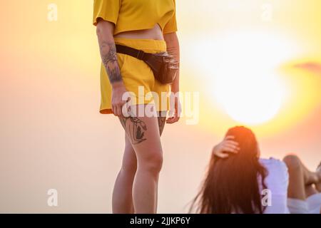 Galle, Sri Lanka - 02 03 2022: Une jeune fille caucasienne tatouée debout devant le soleil couchant dans la soirée. Les gens se détendent et apprécient la vue. Banque D'Images