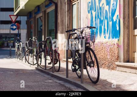 Une photo des bicyclettes garées en rangée sur le trottoir de Trento, en Italie Banque D'Images