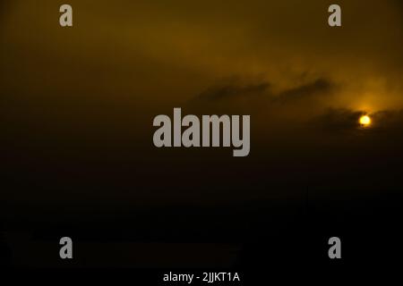 Ciel de coucher de soleil et nuages sombres avec un soleil orange profond dans un cadre orageux. Des nuages illuminés et une présence inquiétante. Atmosphère et mystérieux. Banque D'Images