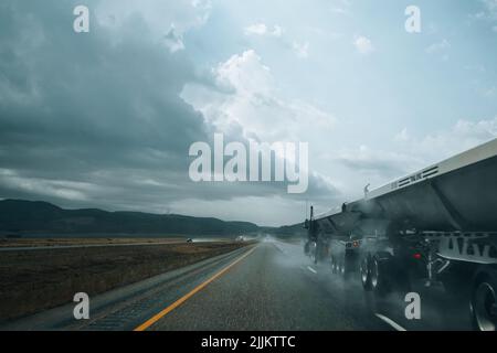 La photo de côté d'une route droite et de camions lors d'un jour de pluie Banque D'Images