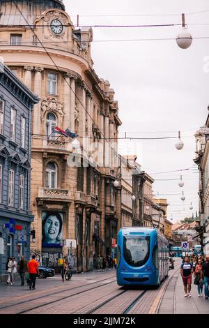 Une photo verticale d'un tramway bleu et de personnes dans les rues de Zagreb, en Croatie Banque D'Images