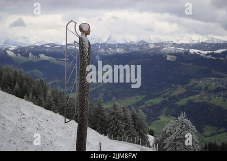 Une statue d'une femelle avec des ailes d'ange sur fond de montagnes couvertes de nature verte en hiver Banque D'Images