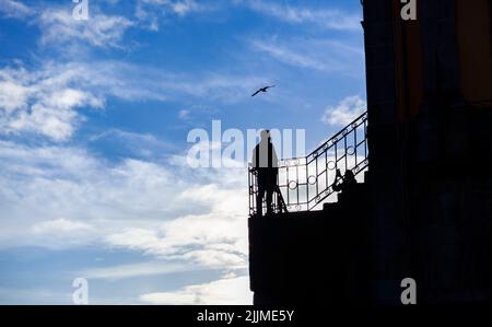 Une silhouette d'une femme prenant en photo un homme sur le balcon Banque D'Images