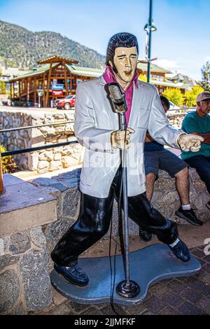 2021-06-01 South Tahoe USA - Statue d'Elvis chantant avec microphone et chaussures en daim bleu sur le flanc du South Tahoe avec des touristes assis sur le mur de pierre Banque D'Images