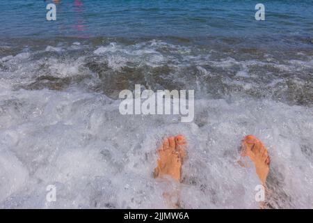 Belle vue sur les jambes de sexe masculin sur la mer pendant la vague. Concept de vacances d'été. Banque D'Images