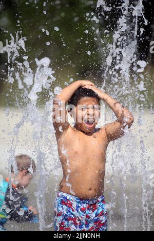 Raleigh, Caroline du Nord, États-Unis. 27th juillet 2022. Le VERT D'AYDEN, âgé de 8 ans, se rafraîchit en passant par les arroseurs de protection dans le John Chvis Memorial Park, alors que les températures atteignent à nouveau le milieu des années 90 à Raleigh, en Caroline du Nord. Une grande partie du pays a également connu des températures supérieures à la moyenne tout au long du mois de juillet. (Image de crédit : © Bob Karp/ZUMA Press Wire) Banque D'Images