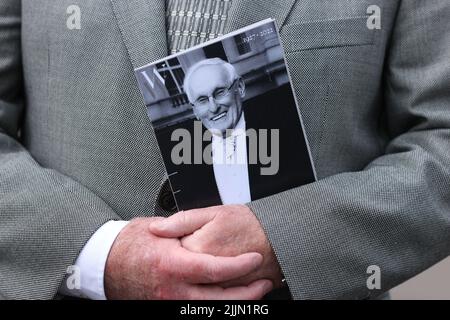 Un deuil tenant un ordre de service à l'extérieur de l'église des pâturages verts, Ballymena, qui a tenu un service d'action de grâce pour le fondateur de Wrightbus, Sir William Wright. Banque D'Images