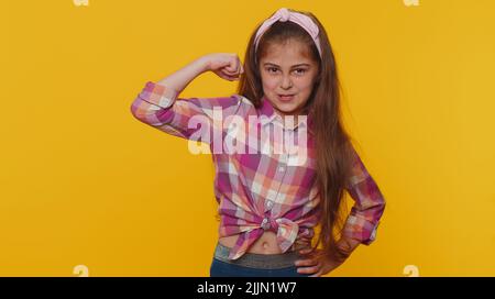 Je suis fort et indépendant. FIT sport jeune enfant jeune préadolescent fille enfant montrant biceps et regardant confiant, sensation de puissance force succès gagner. Petits enfants seuls sur fond jaune studio Banque D'Images