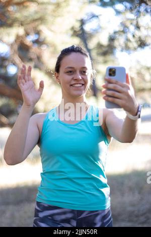 Une photo verticale d'une femme souriante qui parle avec un téléphone portable lors d'un appel vidéo Banque D'Images