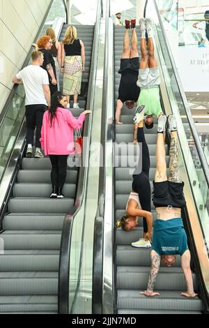 UTILISATION ÉDITORIALE SEULEMENT la gymnaste olympique Nile Wilson (en bas à droite) avec les gymnastes Sophie Brace, Luke Stoney et Ash Watson qui se produit au centre commercial Westfield London pour célébrer le nouveau jour de l'essai national jeudi. Date de la photo: Mercredi 27 juillet 2022. Nile et une équipe de tumblers ont réalisé des cascades telles que le Human Bowling ball, un parcours d'obstacles et des tours de piste aérienne dans l'Atrium de Westfield, offrant un entraînement de cascades gymnastiques un-à-un aux passants. Le crédit photo devrait se lire: Matt Crossick/PA Wire Banque D'Images