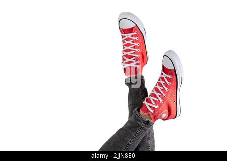 Jambes d'une jeune femme en baskets rouges élégantes sur fond blanc. Banque D'Images
