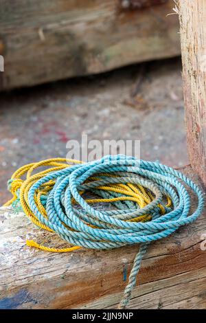 bobines de l'homme fait corde de nylon en matière plastique jaune et bleu sur un quai en grèce, cordes de couleur enroulée, hommes fait cordes et cordage sur le mur. Banque D'Images