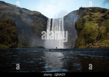 Une vue panoramique de la cascade de Skogafoss sur la rivière Skoga contre le ciel bleu dans le sud de l'Islande Banque D'Images