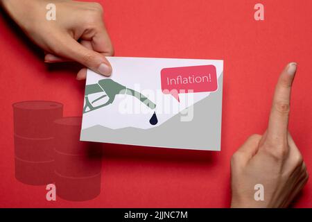 la main femelle tient un morceau de papier avec une buse de pompe à carburant, un graphique et le mot inflation sur elle illustre la hausse des prix du carburant avec une main makin Banque D'Images