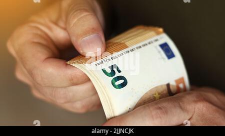 Homme comptant de l'argent. Gros plan des mains masculines comptant un tas de 50 billets en euros. Change de devises étrangères. Calcul de l'argent comptant. Concept de salaire. Banque D'Images