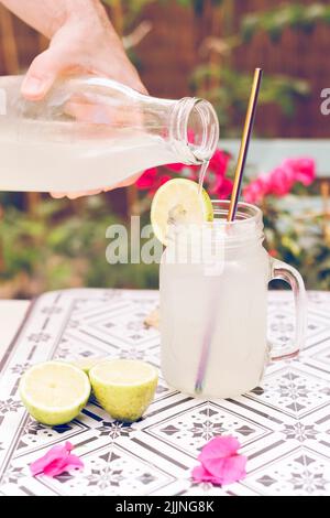 Gros plan d'une femme qui verse un verre de limonade surgelée sur une table de jardin Banque D'Images