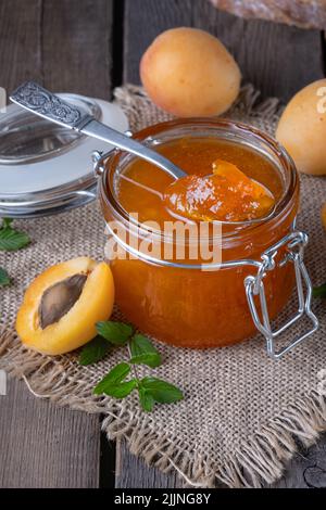 Confiture d'abricots dans un pot en verre sur une ancienne table en bois Banque D'Images