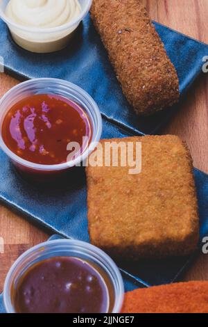 Un cliché vertical de différents types de nuggets frits avec sauces Banque D'Images