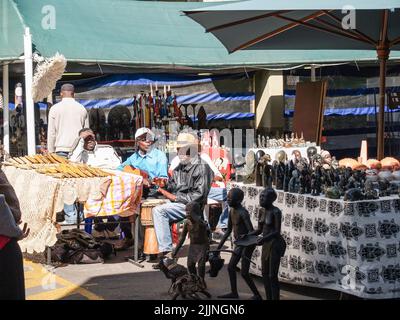 Johannesburg Afrique du Sud - 12 août 2027; hommes africains assis à la table de vente dans le marché de l'artisanat urbain vendant des figures sculptées aux touristes. Banque D'Images