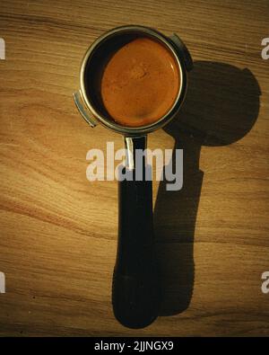 Vue de dessus d'un porte-filtre rempli de café moulu sur une surface en bois Banque D'Images