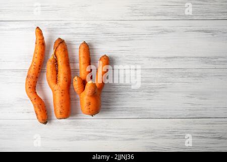 Plusieurs carottes orange mûres laid reposent sur une surface en bois clair Banque D'Images