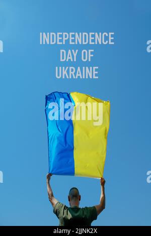 texte jour de l'indépendance de l'ukraine et un homme, vu de l'arrière, agitant le drapeau ukrainien sur le ciel au-dessus de sa tête Banque D'Images