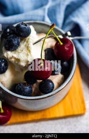 Gros plan de la glace à la vanille avec des bleuets et des cerises frais Banque D'Images