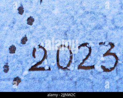 Texte bonne année 2023 sur la neige. Inscription manuscrite 2023 et traces de l'année à venir sur de la neige blanche fraîchement tombée. Fond abstrait pho Banque D'Images