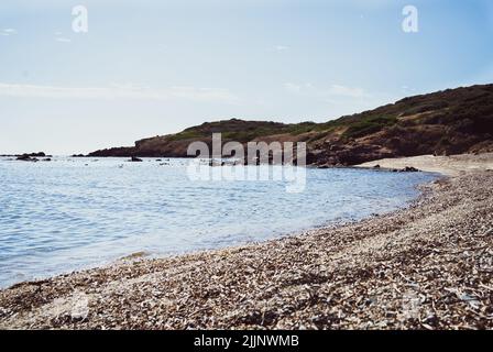 Vue sur la plage de Nora entourée de collines verdoyantes et de rochers Banque D'Images