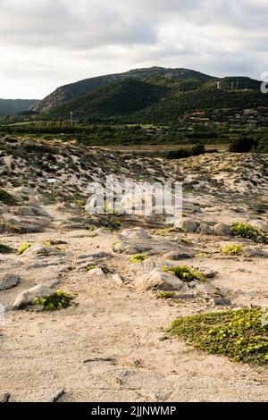 Une photo verticale de la plage rocheuse de Chia en arrière-plan de collines verdoyantes en Sardaigne Banque D'Images