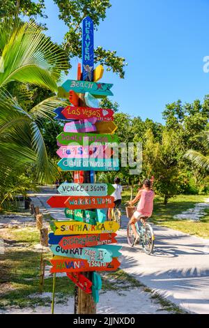 Panneau coloré près d'une piste cyclable sur l'île tropicale la Digue sur seychelles. Panneaux indiquant des destinations célèbres dans le monde entier. Banque D'Images